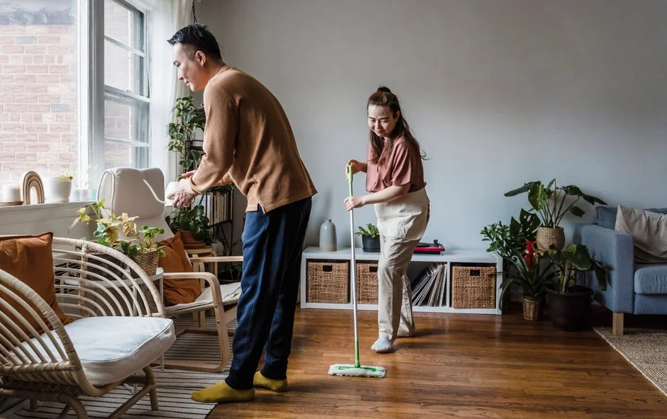 a-woman-in-a-green-shirt-and-black-gloves-vacuuming-a-gray-ottoman-5txz228u4eo